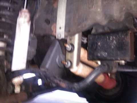 1992 Ford Bronco - Close-up view of a vehicle's undercarriage, showing suspension parts and a black block, with 'SUPERMOTORS' branding.