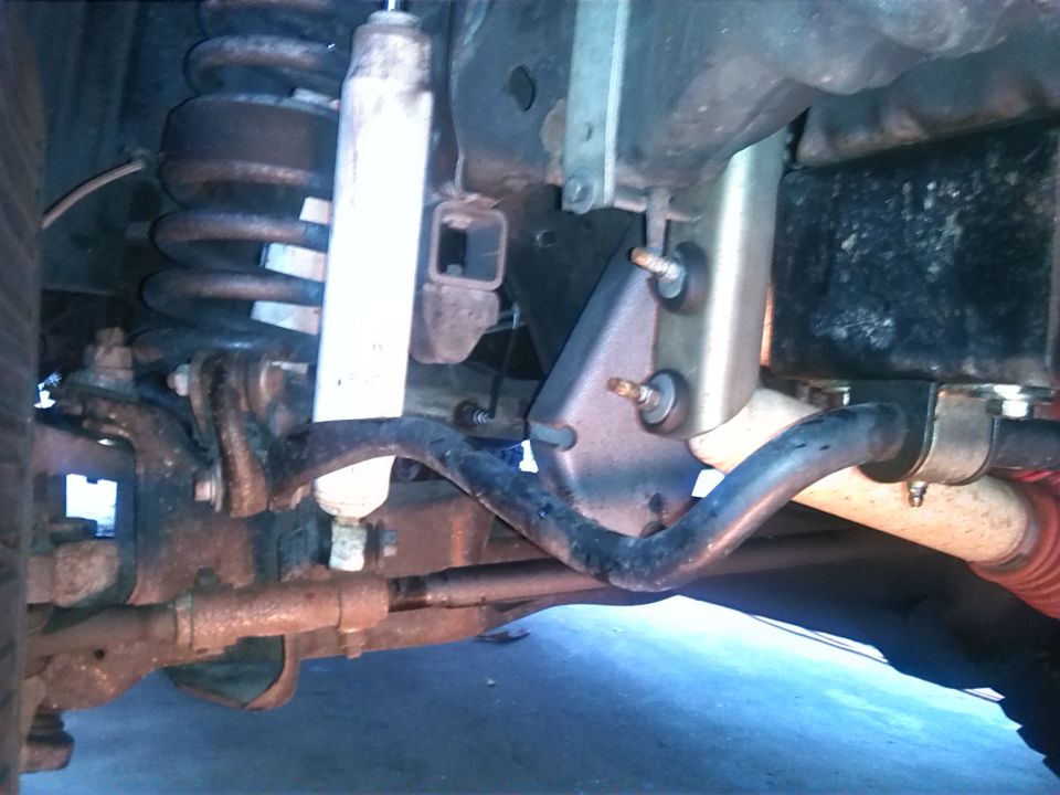 Close-up of vehicle suspension with shock absorber, coil spring, and sway bar visible