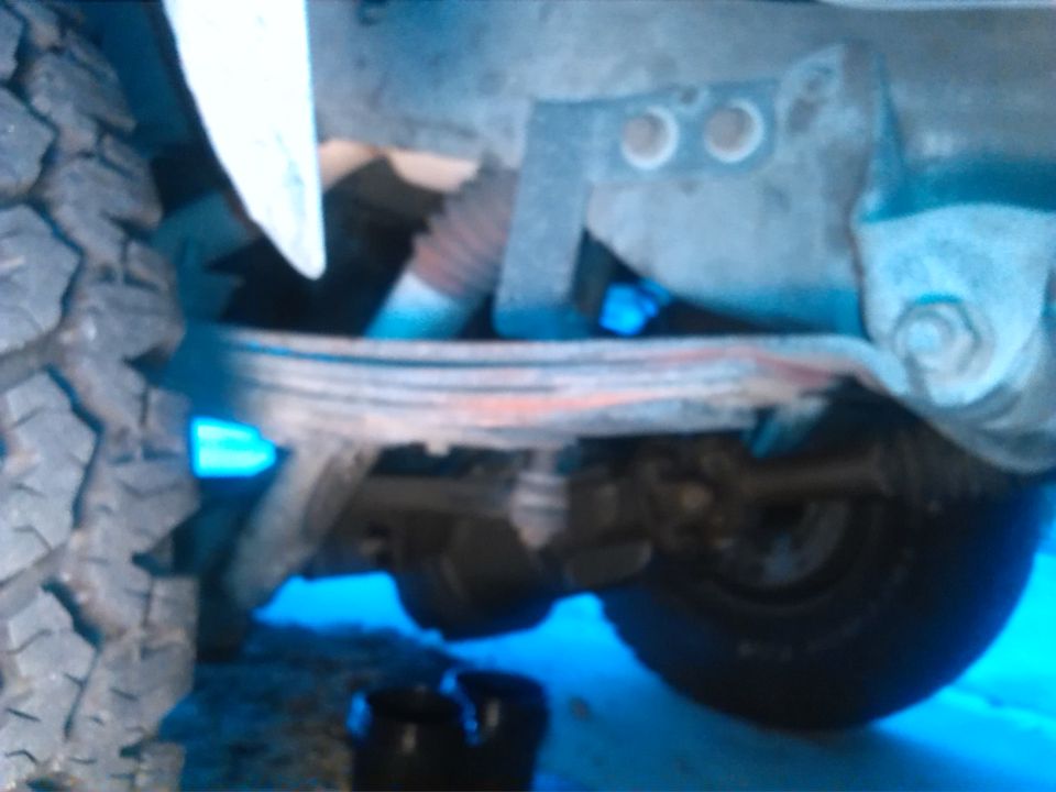 Undercarriage view of a vehicle's leaf spring suspension and tire