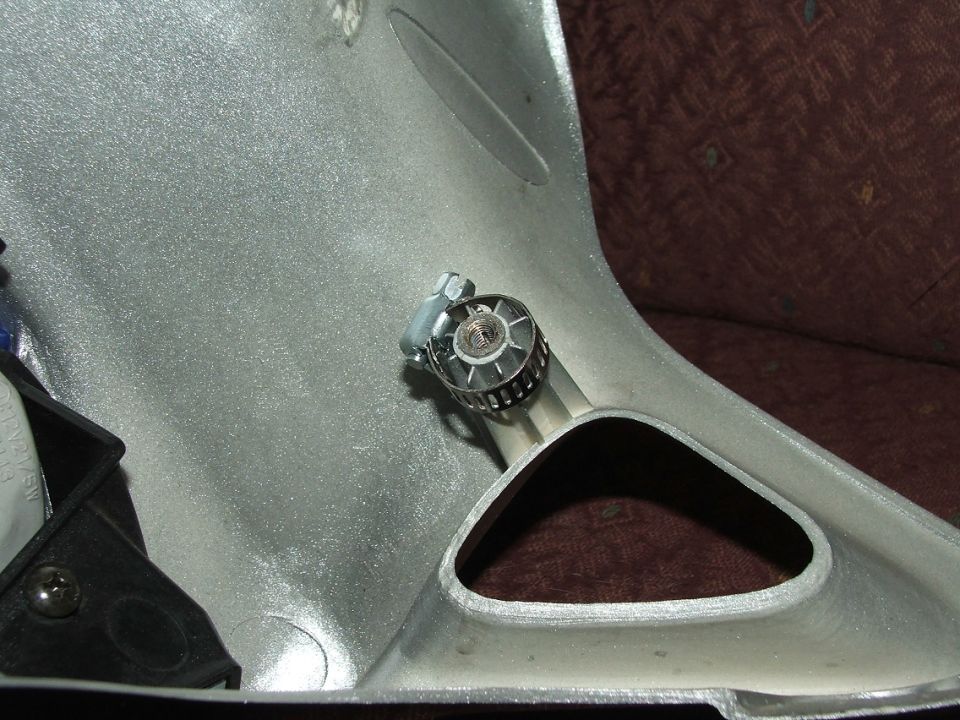 Silver plastic motorcycle fairing with a hose clamp attached to a metal bracket