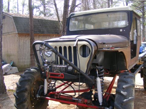Front view of a modified off-road vehicle with large tires, winch, and custom roll cage
