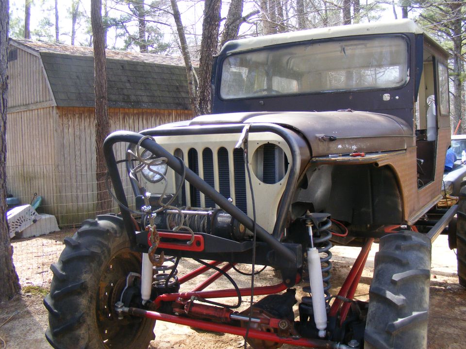 Front view of a modified off-road vehicle with large tires, winch, and custom roll cage