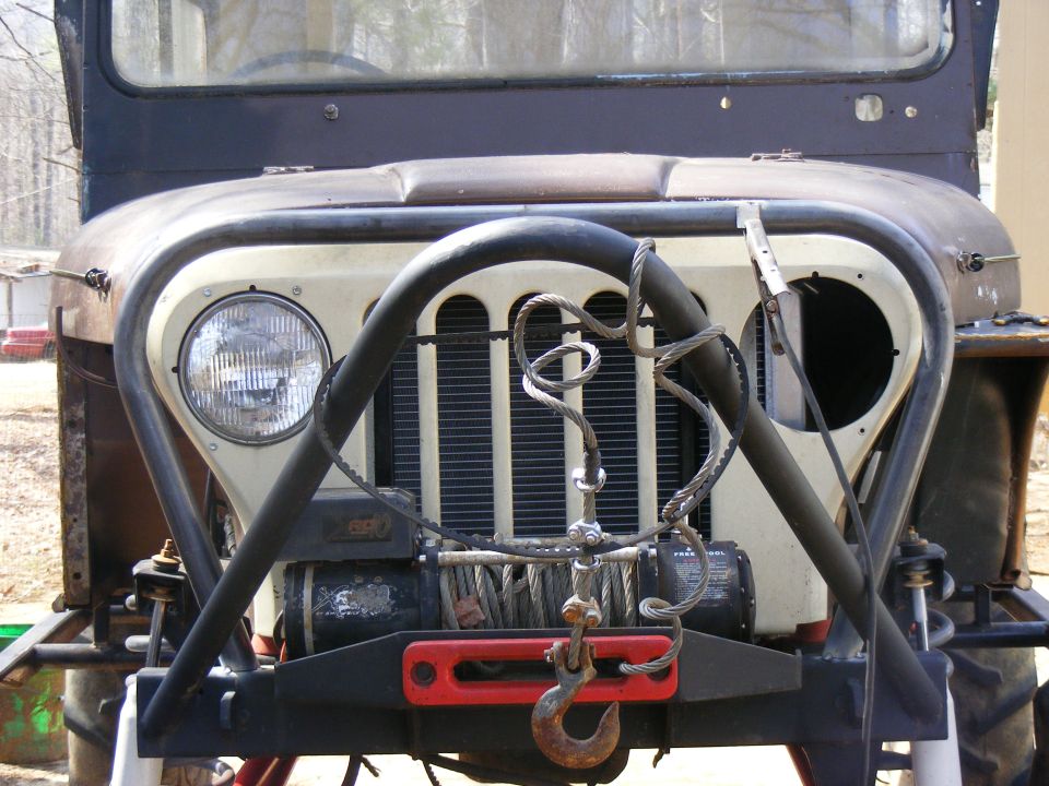 Jeep CJ front end with a winch mounted on the bumper. The grille has vertical slats