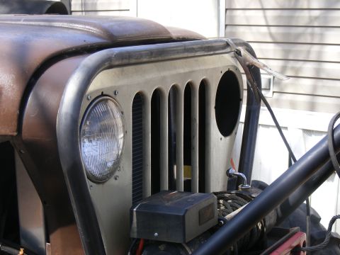 Front end of a rusty Jeep CJ with a brush guard and winch