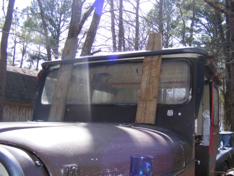 Brown SUV rear window with wooden supports, hood in foreground