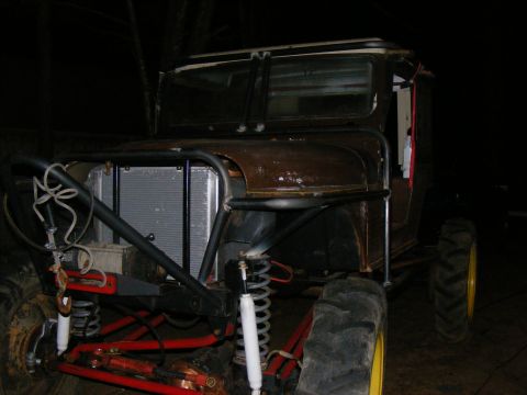 Modified off-road vehicle with custom roll cage, large tires, and exposed radiator