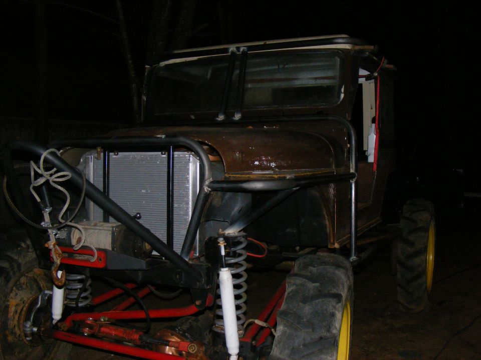 Modified off-road vehicle with custom roll cage, large tires, and exposed radiator
