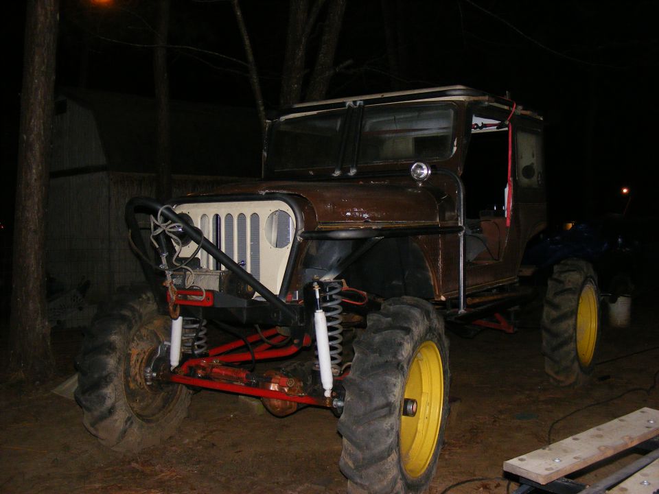 Brown modified off-road vehicle with large tires and yellow rims, front view