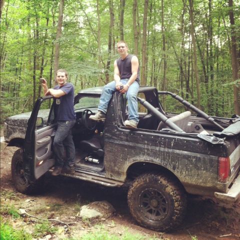 1995 Ford Bronco - Two men pose with a black Ford Bronco in a forest setting.