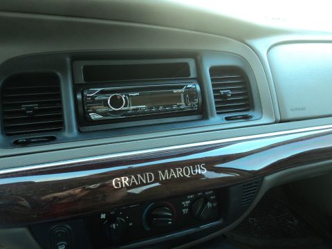 2004 Mercury Grand Marquis - Interior view of a 2004 Mercury Grand Marquis dashboard, showing the center console with an aftermarket stereo and wood grain accents.