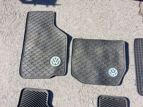 2002 Volkswagen Jetta - Black rubber Volkswagen floor mats with a scale pattern and circular VW logo are shown on asphalt.