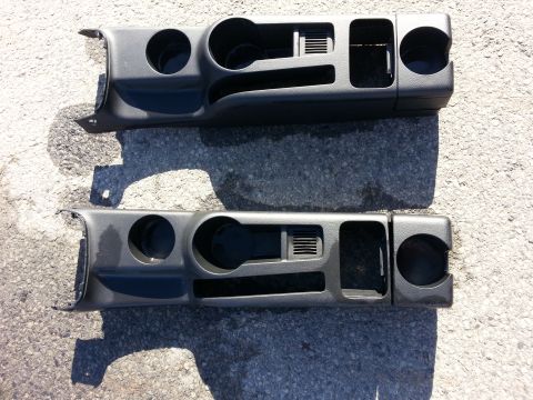 2002 Volkswagen Jetta - Two dark gray dashboard trim pieces, each multiple cup holders and air vents, are laid out on a textured surface.
