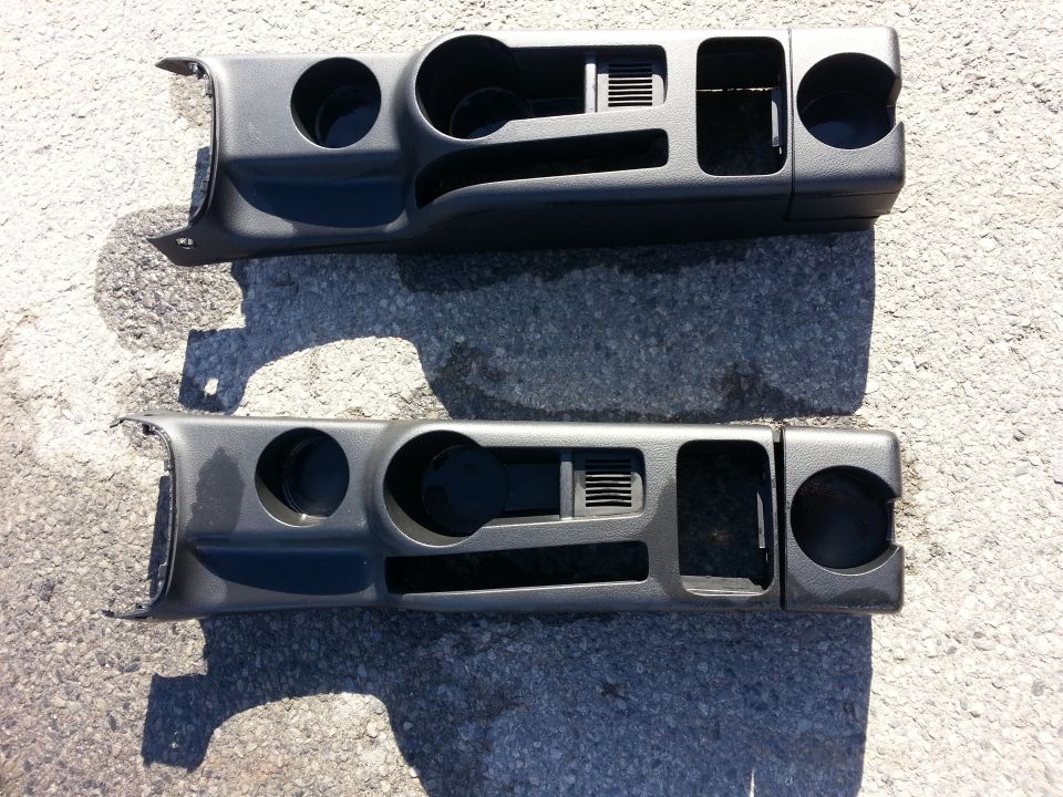 Two dark gray dashboard trim pieces with cup holders and air vents