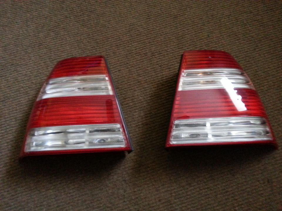Pair of red and clear car tail lights on a brown carpeted surface