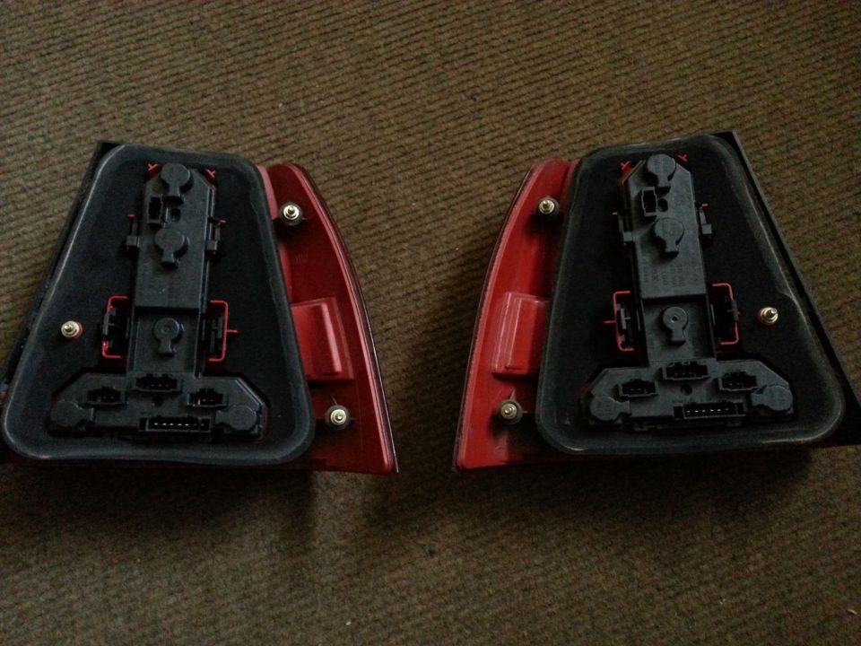 Two car tail light assemblies, viewed from the back with wiring connectors visible