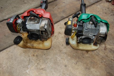 2006 Honda RANCHER - Two string trimmers, one red and one green, are shown from the engine perspective on a concrete floor.