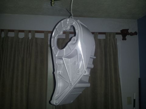 1988 Ford Bronco - A large, light gray painted metal component hangs from a wire indoors, likely in a garage or workshop.