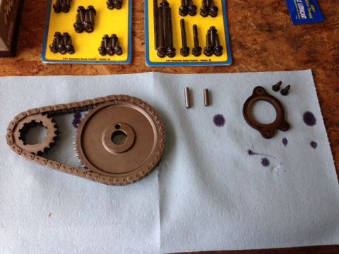1996 Ford Bronco - A timing chain and gear set, along with pins and a gasket, are laid out on a blue shop towel, ready for installation.