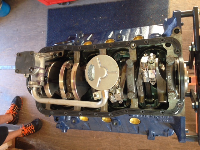 Engine block with crankshaft and oil pump visible. Someone's feet are in the lower left