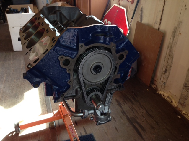 Blue engine block on an orange stand, showing timing chain and gears