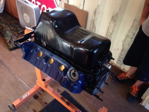 1996 Ford Bronco - Engine block and oil pan assembly on a stand, with a person in the background.