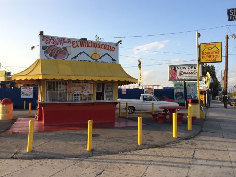 1964 Ford Ranchero - A white pickup truck is parked beside a Mexican food stand with outdoor seating.
