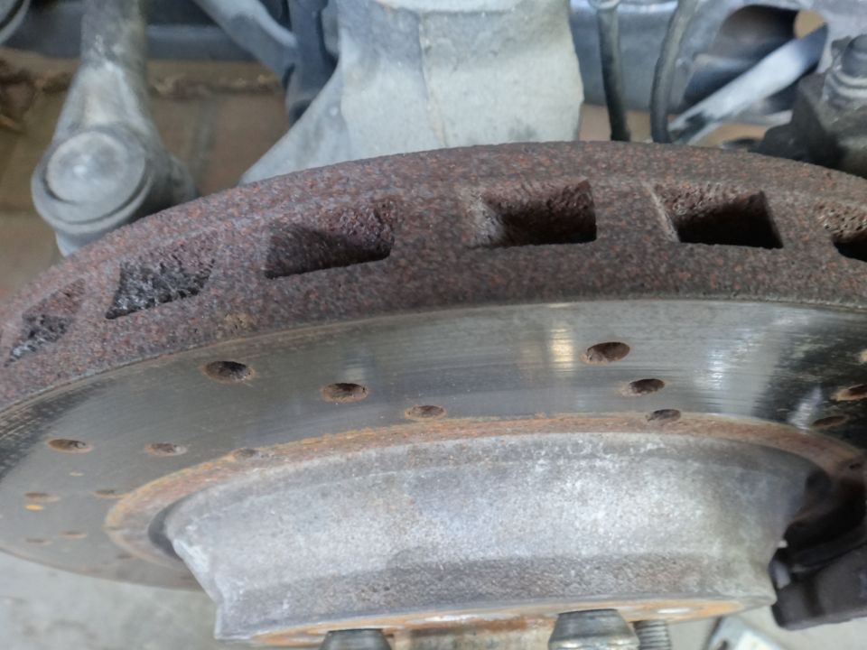 Close-up of a heavily rusted brake rotor with visible wear marks and cooling vents