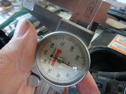 1993 Ford Taurus - A dial caliper is used to measure an engine component, with the dial indicating a measurement.