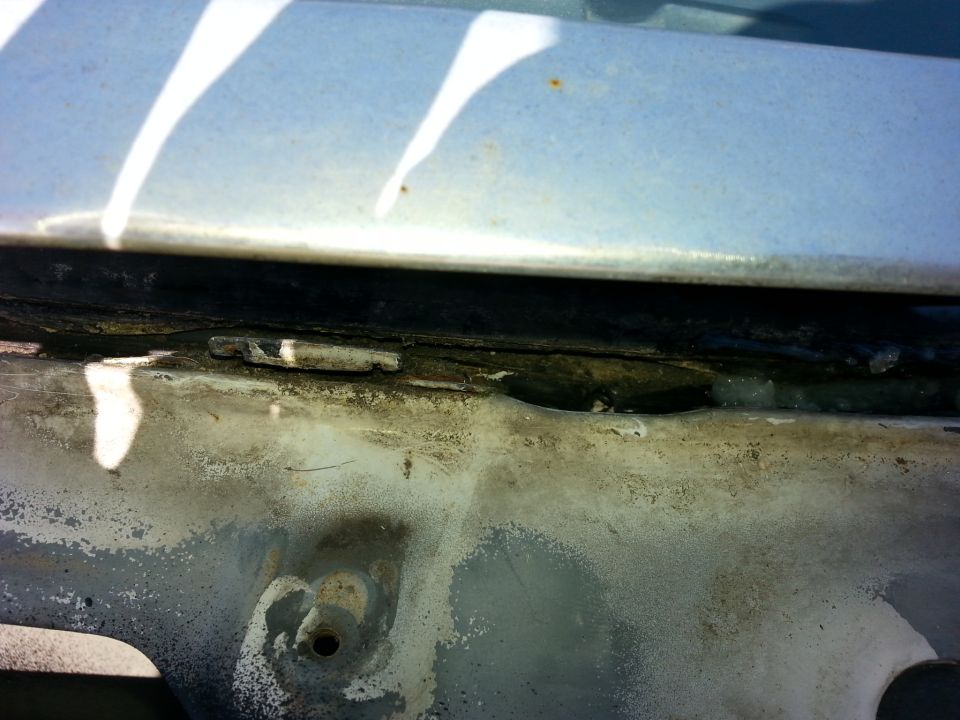 this small hole, which I'm pretty sure it there to drain water into the trough is underneath the windshield trim..it was a little clogged up with debris, so I cleared it out. while I was there, I also put a bead of silicone in that lower gap between the windshield and the body.