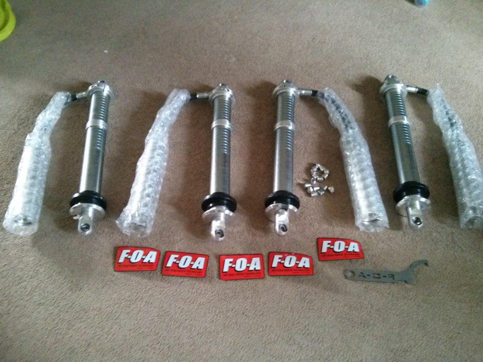 Four F-O-A shock absorbers and a wrench on a carpeted surface