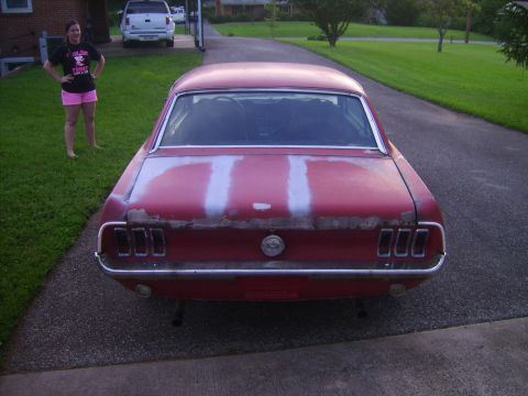 1968 Ford Mustang - Rear view of a red 1968 Ford Mustang showing primer patches on the trunk lid.
