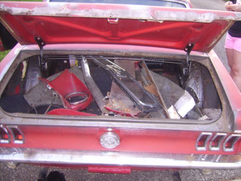1968 Ford Mustang - The trunk of a red 1967 Ford Mustang is filled with various car parts and debris.
