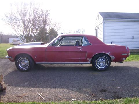 1968 Ford Mustang - Red 1968 Ford Mustang coupe with a hood scoop, parked outside.