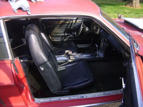 1968 Ford Mustang - Interior view of a red 1968 Ford Mustang, showing the black seats and dashboard.