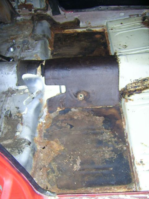 1968 Ford Mustang - The interior floor pan of a vehicle exhibits significant rust and corrosion, indicating structural damage.