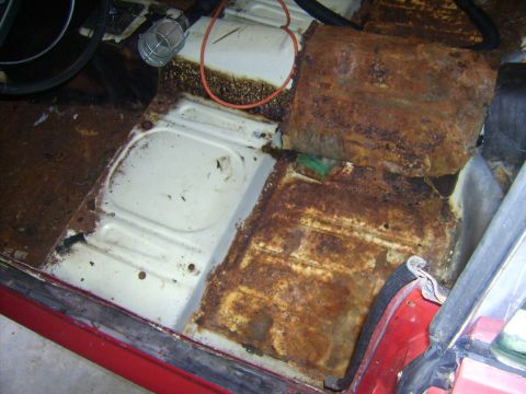 1968 Ford Mustang - The interior floor of a vehicle shows extensive rust and corrosion, indicating structural damage.