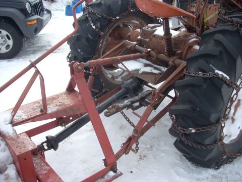 1963 Hummer H3 - This image shows the rear of a tractor with tire chains, with a Jeep visible in the background during winter.