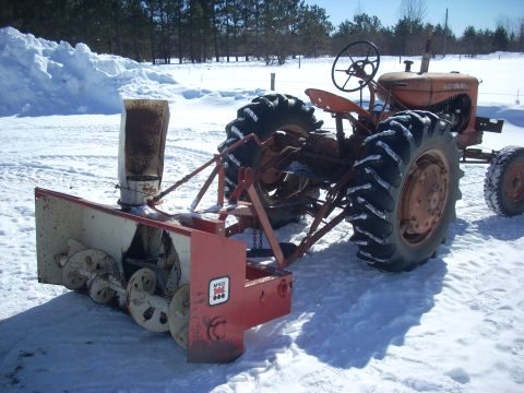 1963 Hummer H3 - An orange tractor is equipped with a snowblower attachment, ready for winter conditions.