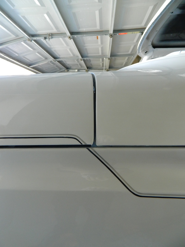 White vehicle body panels with a black pinstripe detail and a visible seam between panels