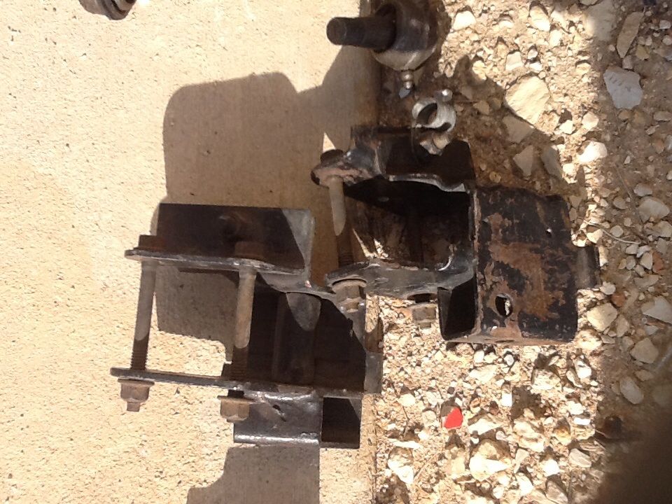 Engine mount bracket with bolts and rust, lying on the ground