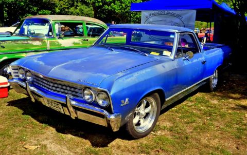 1964 Mercury Monterey - A blue pickup truck is parked next to a green car under a tent with a banner.