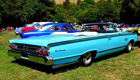 1964 Mercury Monterey - A light blue 1964 Mercury Monterey convertible is parked on a grassy field with other classic cars in the background.