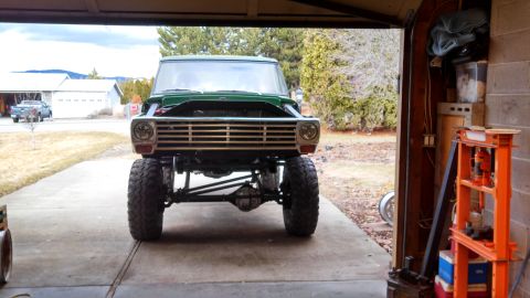 1967 Ford F-250 - Front view of a lifted green pickup truck with its hood open, parked inside a garage.