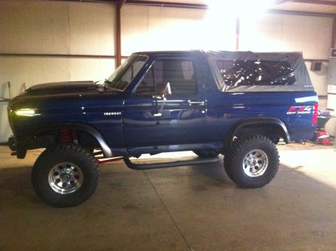 1982 Ford Bronco - This lifted 1982 Ford Bronco features a dark blue paint job, a soft top, and an "FX4 OFF ROAD" decal on the rear fender.
