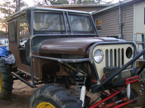 Custom off-road vehicle with large tires, roll cage, and winch. Front grille is cream-colored