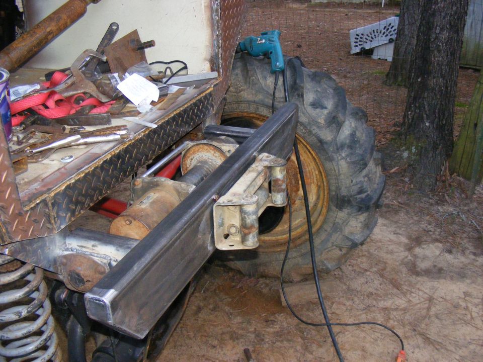 Close-up of a large tire and suspension components with tools and a drill nearby