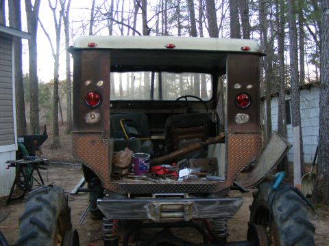Brown off-road vehicle rear view, diamond plate accents, open tailgate with tools
