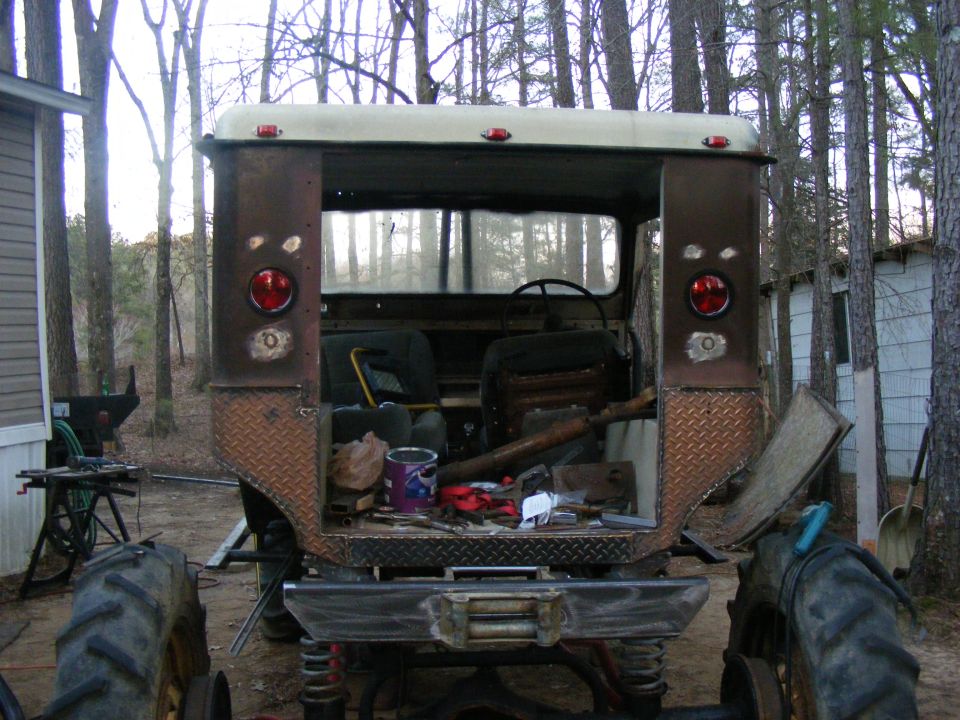 Brown off-road vehicle rear view, diamond plate accents, open tailgate with tools