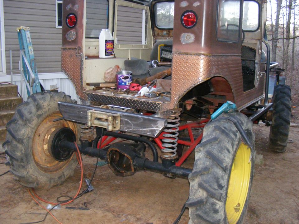 Rear view of a heavily modified vehicle with large tractor tires and a custom bumper