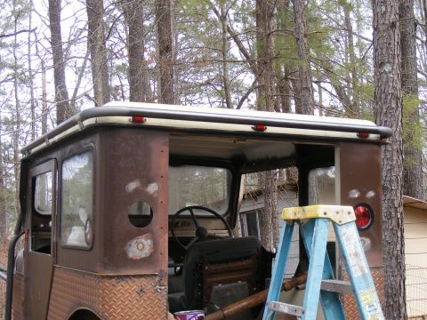 Rusted off-road vehicle with diamond plate rear quarter panels and a roof rack